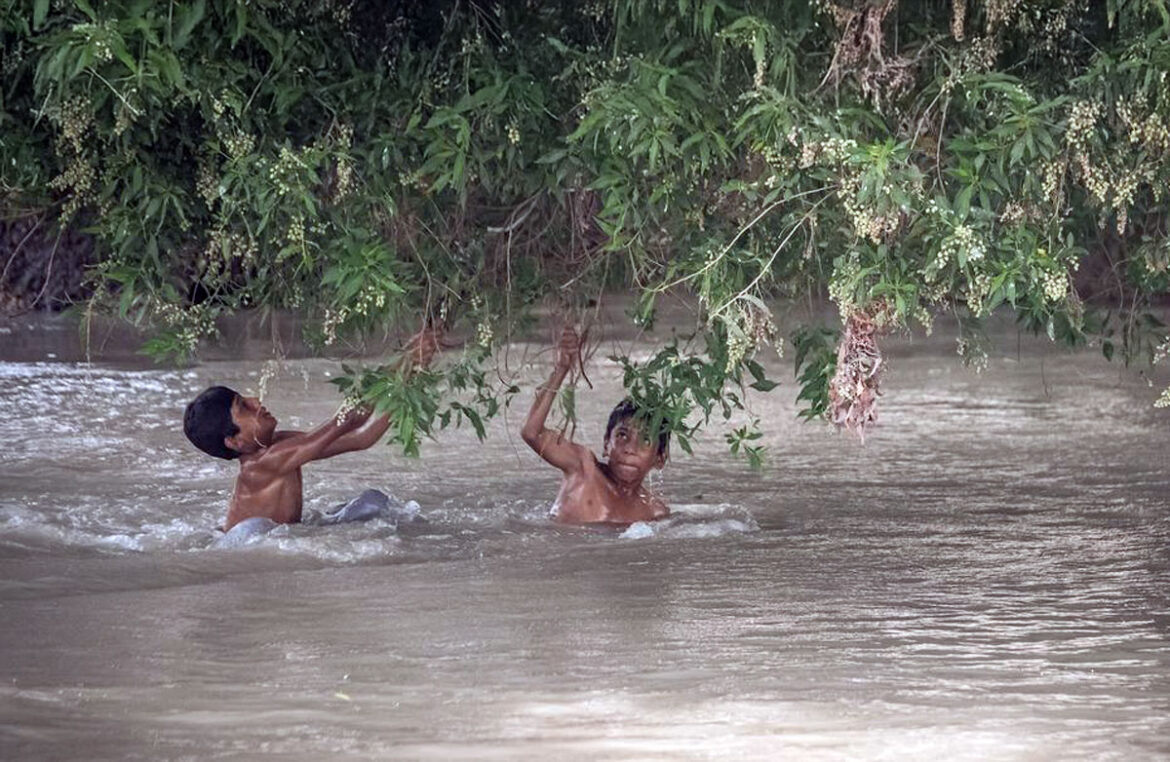 Niños vadean un canal inundado en Pakistán, donde las lluvias monzónicas de este año han dejado a muchas familias sin hogar, sin agua potable y sin escolarización (foto de archivo).